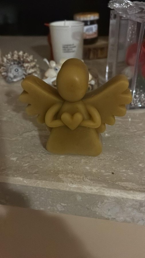 Candela in cera d'api a forma di angelo che tiene un cuore