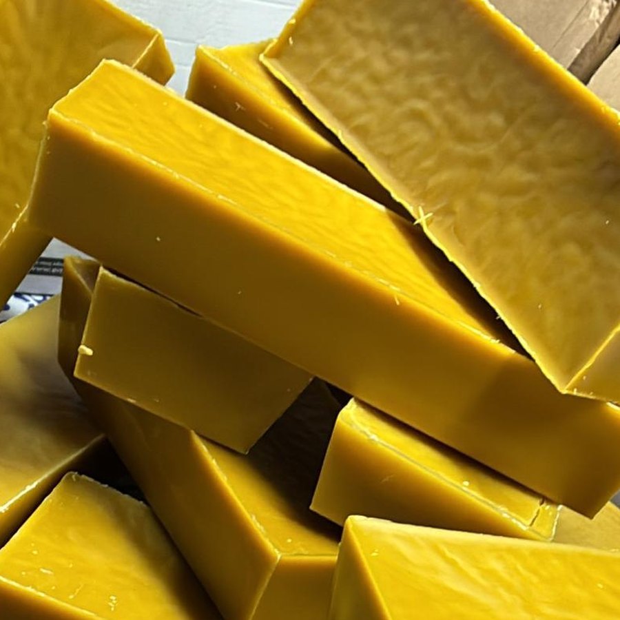 Un cartone pieno di lingotti di cera d'api pura, gialli e lucidi