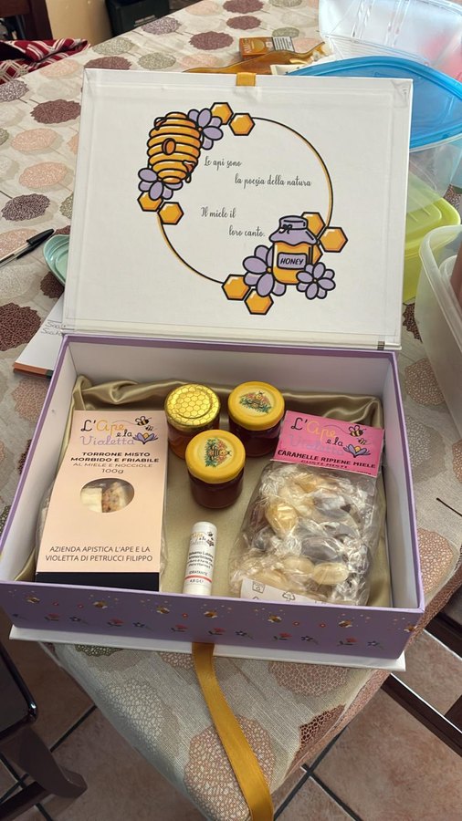 Cofanetto regalo aperto con torrone, tre vasetti di miele, caramelle e balsamo labbra